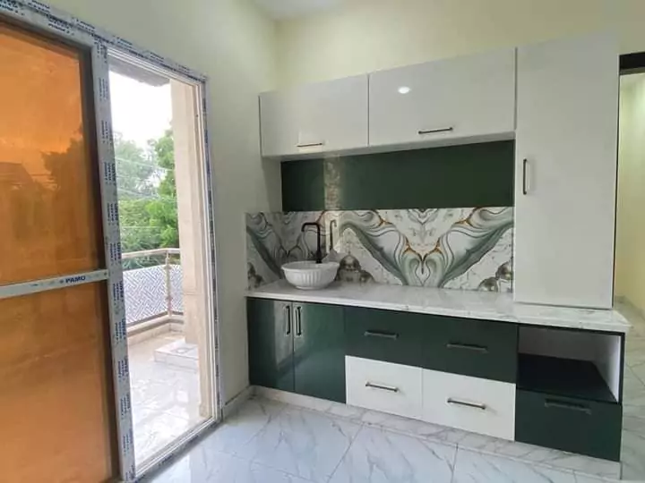 Luxury Townhouse for Sale in PECHS Block 2 Main Khalid Bin Waleed Road Karachi at Prime Location (4) Modern kitchen with white and green cabinets, decorative backsplash, sink, and balcony door in luxury townhouse for sale in P