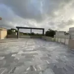 Spacious Rooftop Terrace Of Luxury Townhouse For Sale In Pechs Karachi With Gray Tiled Flooring, Central Pergola, Railings An