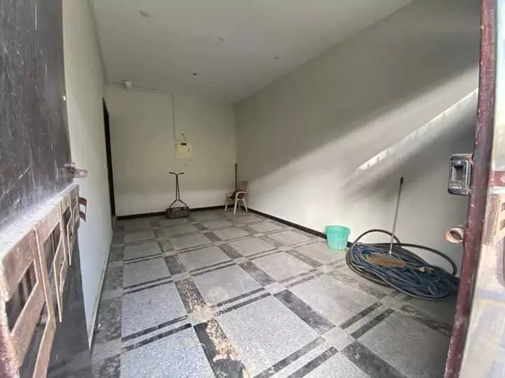 Luxury Townhouse for Sale in PECHS Block 2 Main Khalid Bin Waleed Road Karachi at Prime Location (7) Spacious utility garage with checkered tile floor, cleaning tools, chair, and electrical panel in townhouse for sale in PECHS