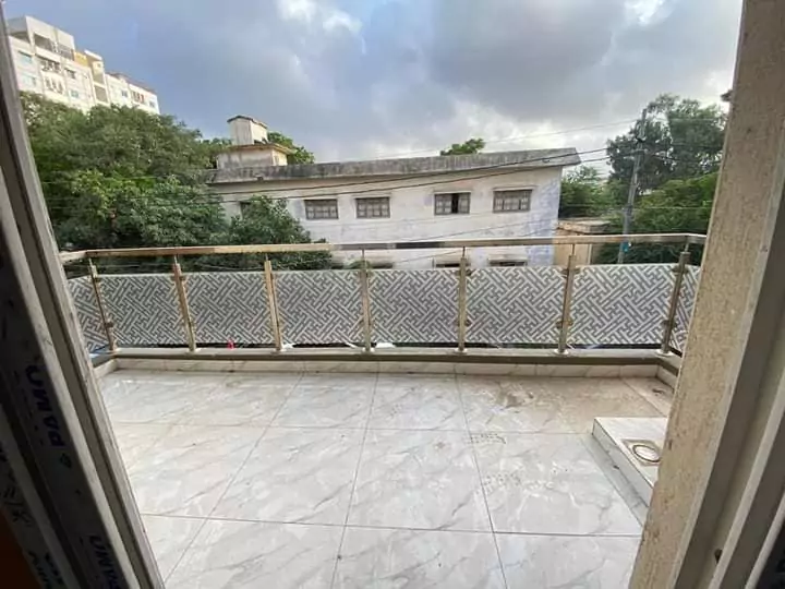 Luxury Townhouse for Sale in PECHS Block 2 Main Khalid Bin Waleed Road Karachi at Prime Location (8) Spacious balcony with light marble tiles and wooden lattice railing overlooking greenery and buildings in PECHS townhouse for