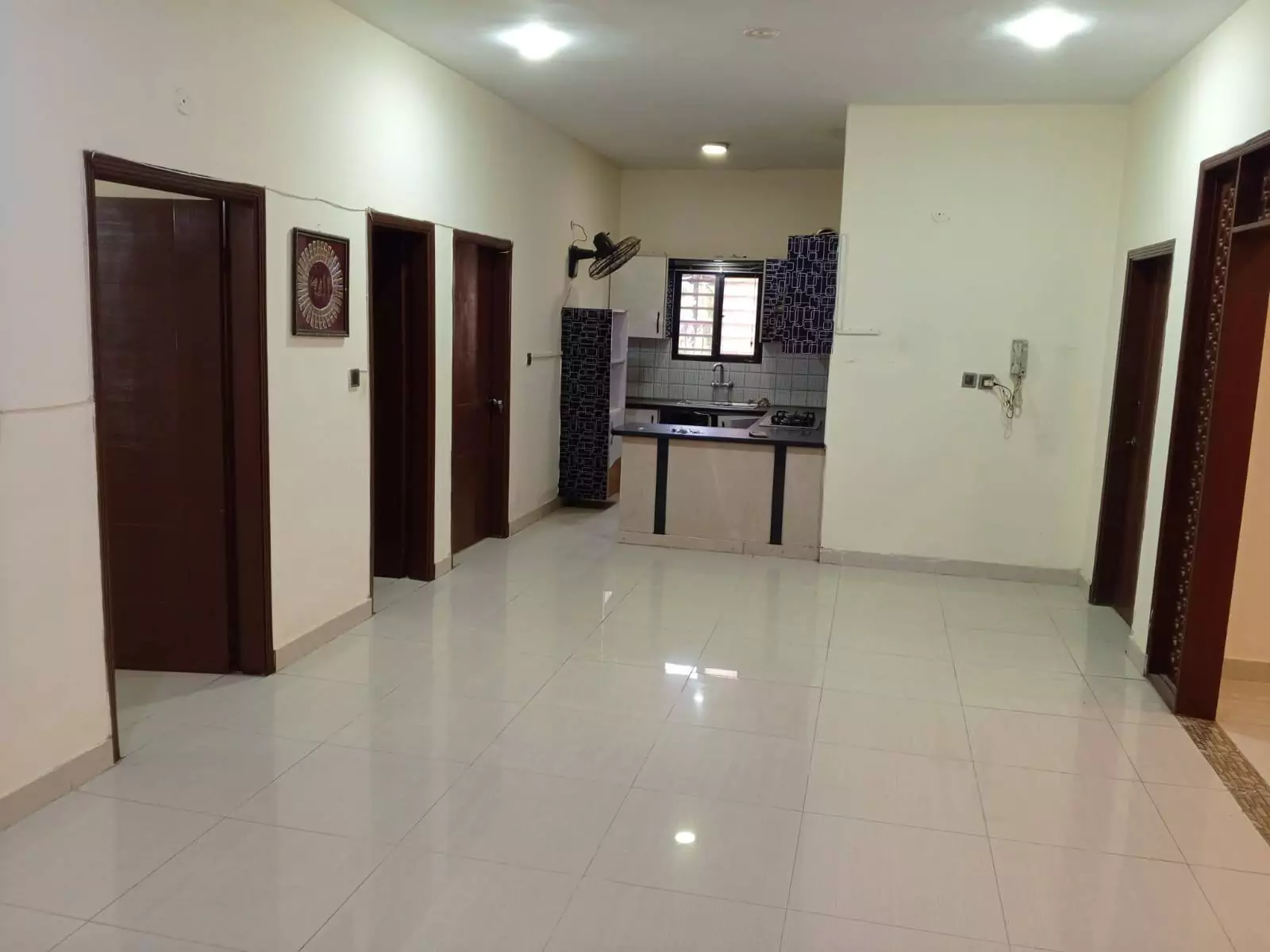 Luxury 3-Bedroom Portion for Rent in PECHS Block 6, Karachi (1) Spacious hallway with wooden doors to bedrooms and compact kitchenette in luxury 3-bedroom portion for rent in PECHS Block 6,