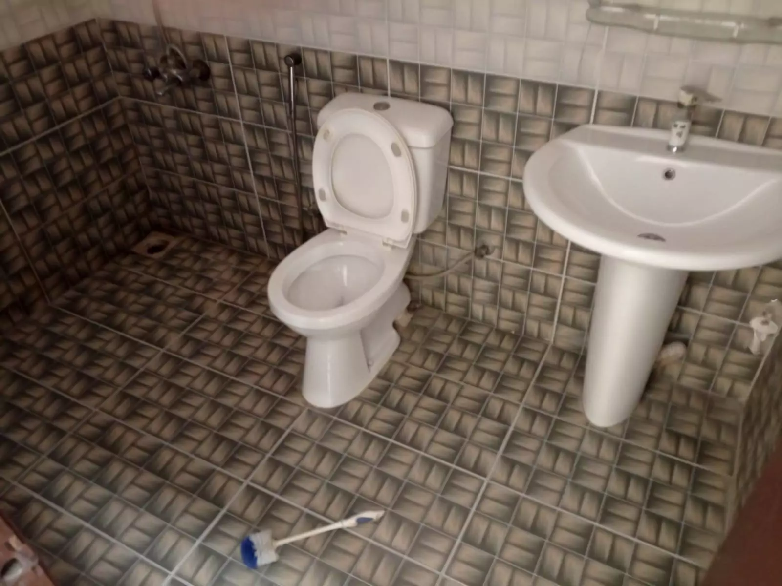 Luxury 3-Bedroom Portion for Rent in PECHS Block 6, Karachi (4) Bathroom with white toilet, pedestal sink, brown mosaic tiles in luxury 3-bedroom portion for rent in PECHS Block 6, Karachi