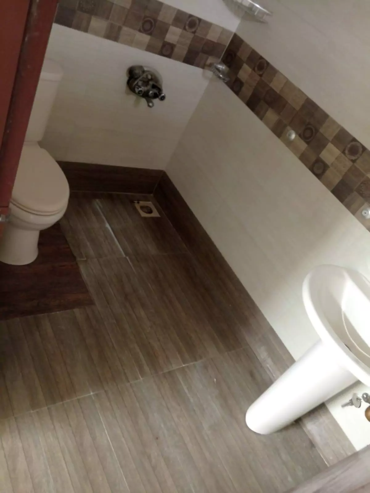 Luxury 3-Bedroom Portion for Rent in PECHS Block 6, Karachi (6) Modern bathroom with white toilet, pedestal sink, brown tiled borders and wooden-look floor in luxury 3-bedroom portion for r