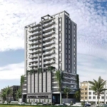 Modern Multi-Story Angel Homes Residential Tower With Glass Balconies, Green Base, Palm Trees, And Urban Surroundings