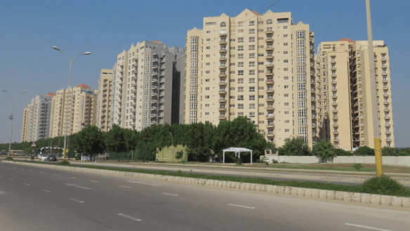 Row Of Modern Beige High-Rise Apartment Buildings Along Wide Boulevard With Palm Trees And Streetlights