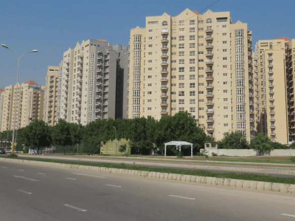 Row Of Modern Beige High-Rise Apartment Buildings Along Wide Boulevard With Palm Trees And Streetlights
