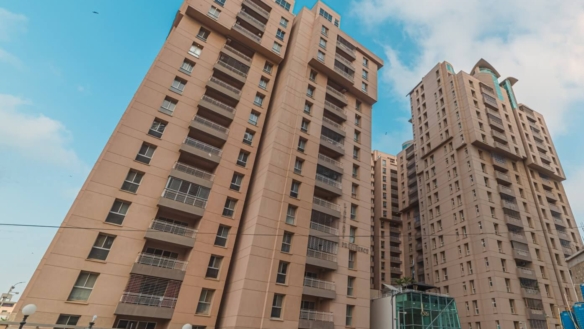 Tall Modern Beige Apartment Towers With Balconies At Lakhani Presidency In Karachi, Gated Entrance And Parked Vehicles