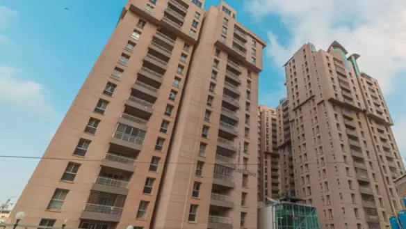 Tall Beige High-Rise Towers Of Lakhani Presidency Apartment Complex With Balconies, Modern Entrance Gate, And Parked Cars