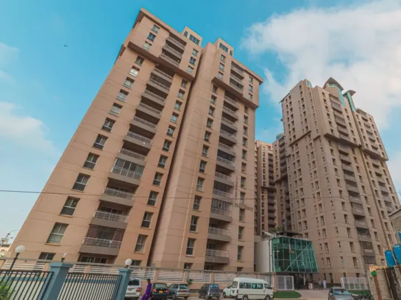 Tall Beige High-Rise Towers Of Lakhani Presidency Apartment Complex With Balconies, Modern Entrance Gate, And Parked Cars