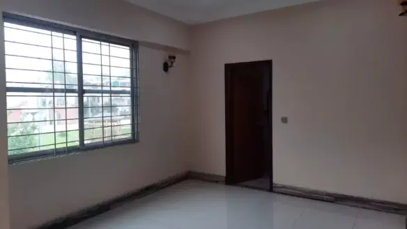 Spacious Empty Room In Karachi Beach Residency Flat, Clifton Block 3, With Beige Walls, White Tiled Floor, Large Grilled Wind