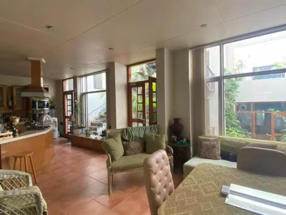 Spacious Open-Plan Kitchen, Dining, And Living Area With Wooden Cabinets, Island Counter, Large Glass Windows, Sofa, Dining T