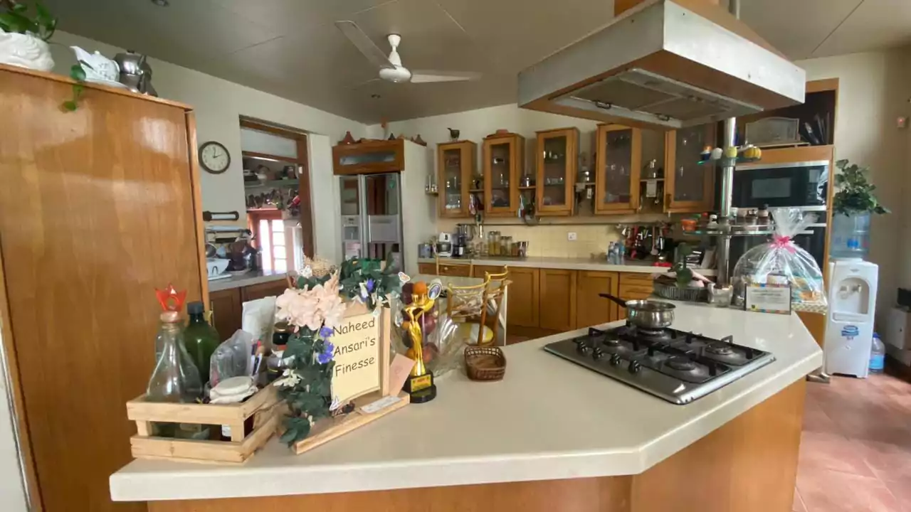 Elegant 500 Square Yards Bungalow for Sale in DHA Phase 6, Karachi (10) Spacious wooden kitchen with central island, gas stove, cabinets, microwave, fridge in elegant 500 sq yd bungalow for sale in