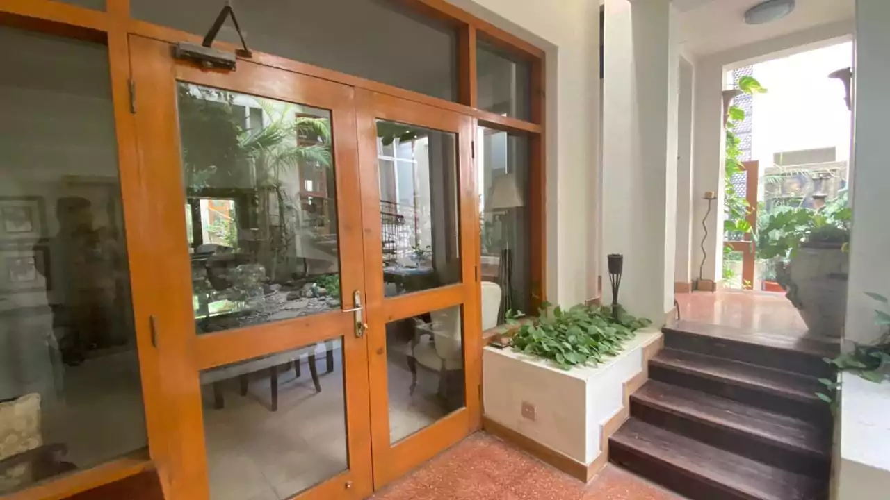 Elegant 500 Square Yards Bungalow for Sale in DHA Phase 6, Karachi (13) Elegant wooden-framed glass double doors at bungalow entrance in DHA Phase 6, with indoor dining area view, potted plants, an
