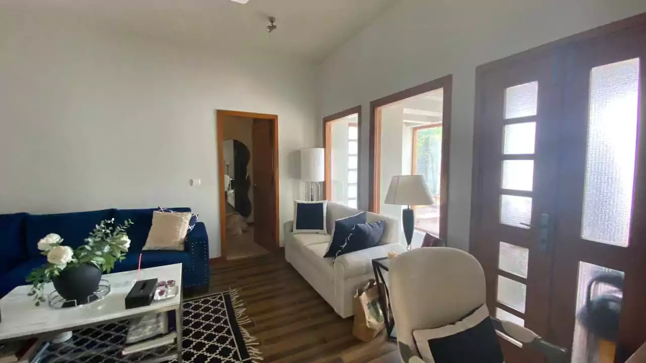 Elegant 500 Square Yards Bungalow for Sale in DHA Phase 6, Karachi (14) Elegant living room in DHA Phase 6 bungalow with navy blue sofa, white couch, large wooden windows, hardwood floors, modern l