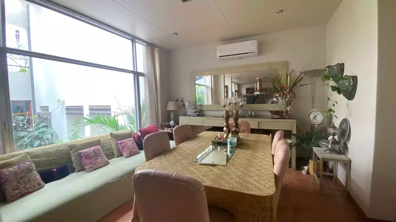Elegant 500 Square Yards Bungalow for Sale in DHA Phase 6, Karachi (2) Elegant dining room in 500 sq yd bungalow DHA Phase 6: large windows with garden view, long wooden table pink chairs, green s