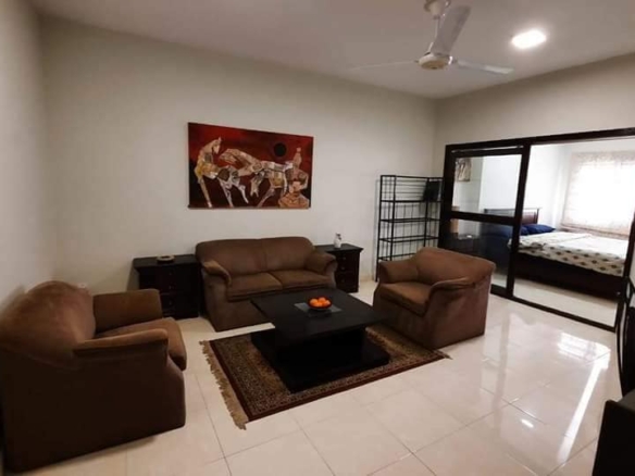Living Room With Brown Leather L-Shaped Sofa, Armchairs, Coffee Table, Ceiling Fan, Wall Art, Sliding Glass Door To Bedroom I