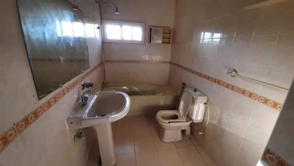 Bathroom with pedestal sink, white toilet, bathtub, showerhead, mirror, tiled walls and floor in DHA Phase 4 portion