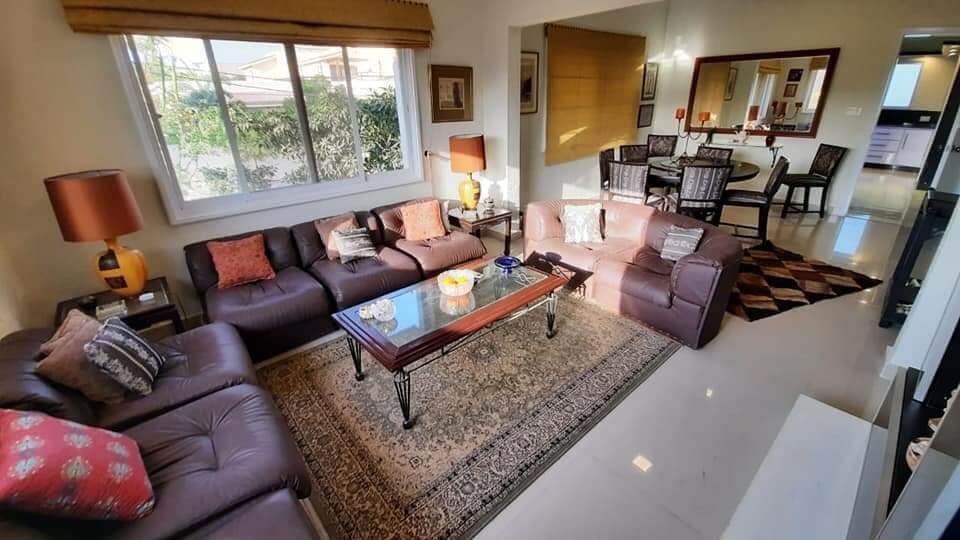 Fully Furnished Portion for Rent in DHA Phase 4, Karachi (7) Spacious living room with brown leather sofas, glass coffee table, oriental rug, dining set in fully furnished portion for re