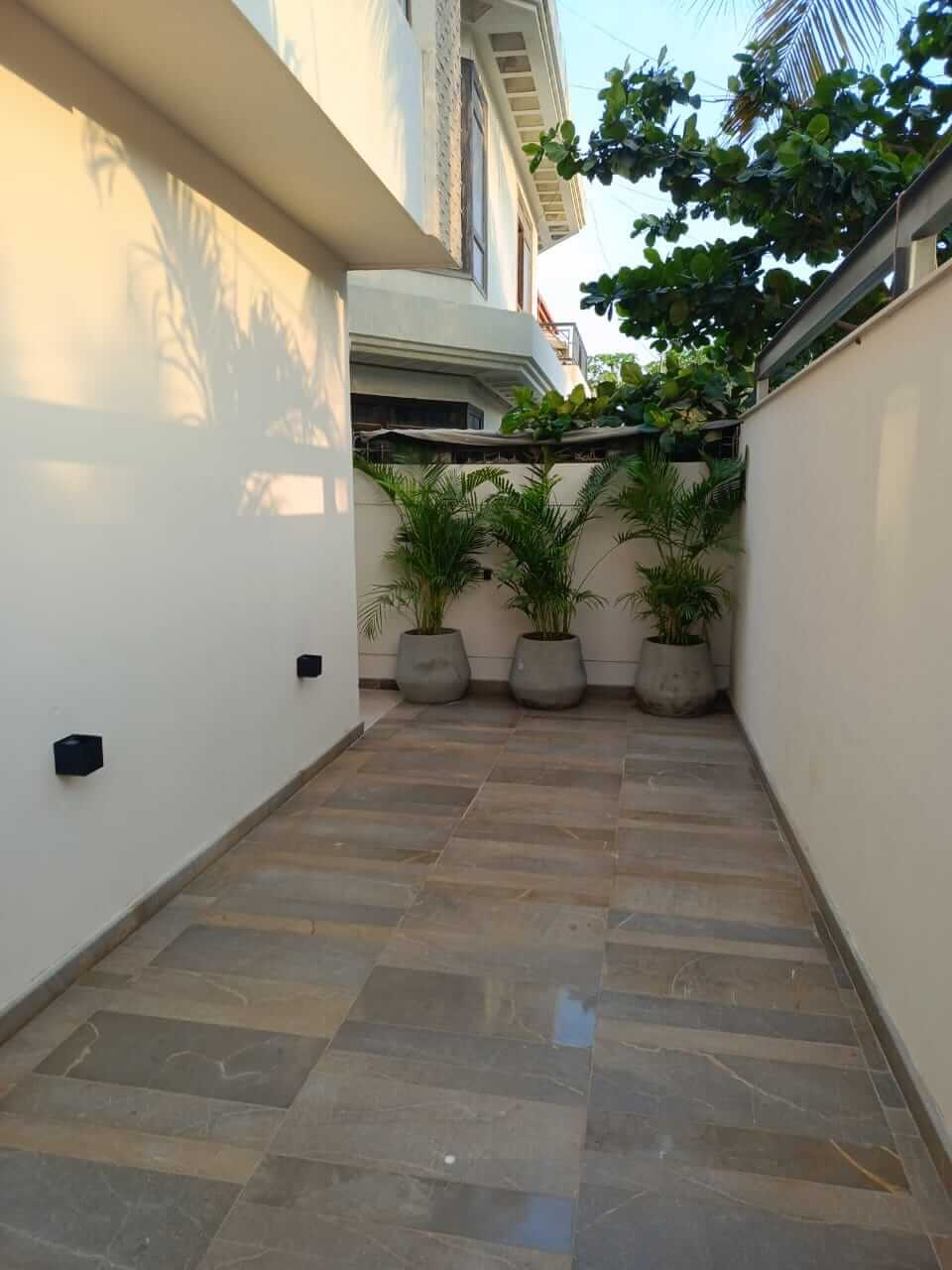 Brand New Stylish Bungalow For Rent in DHA Phase 4 Karachi (5) Spacious tiled courtyard with potted palms and modern white walls in brand new stylish bungalow for rent in DHA Phase 4 Karac