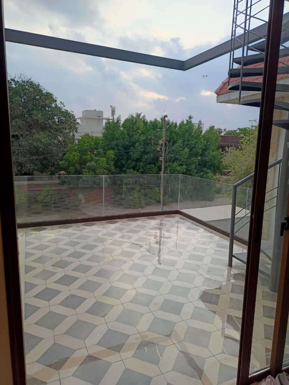 Brand New Stylish Bungalow For Rent in DHA Phase 4 Karachi (7) Spacious modern balcony with diamond-patterned tiles, glass railings, metal staircase in bungalow for rent in DHA Phase 4 Kar