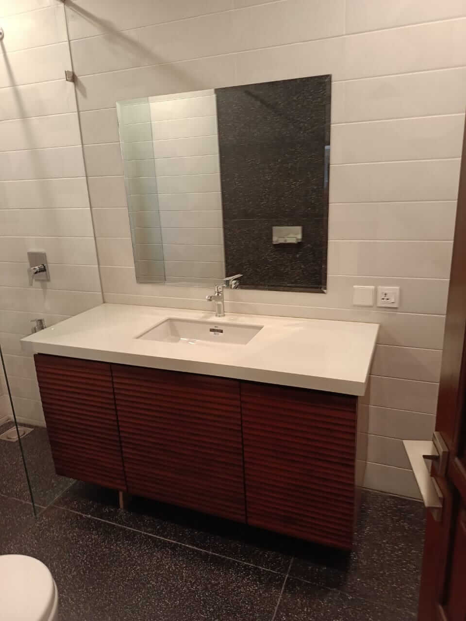 Brand New Stylish Bungalow For Rent in DHA Phase 4 Karachi (8) Modern bathroom with wooden slatted vanity, white sink, large mirror, glass shower, and toilet in DHA Phase 4 bungalow for re