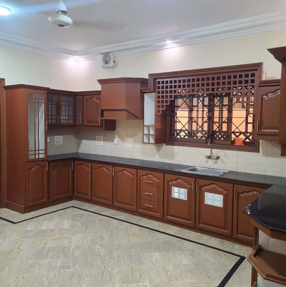 Supreme Luxury Bungalow for Sale in DHA Phase 6, Karachi (3) Luxurious kitchen with wooden cabinets, granite countertops, sink and window in DHA Phase 6 bungalow