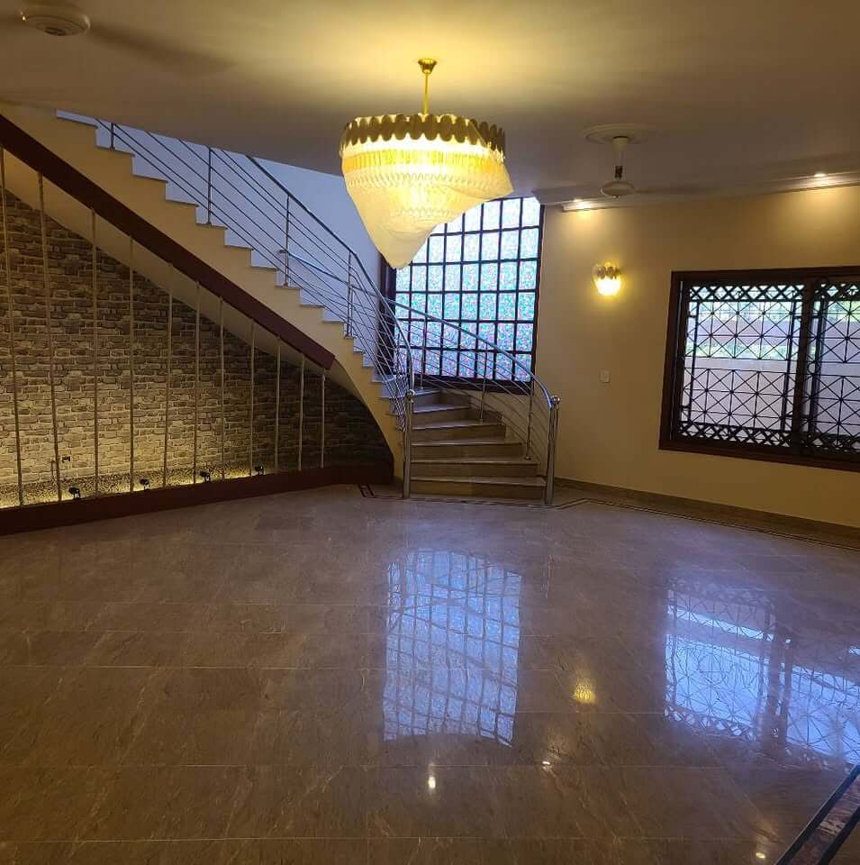 Supreme Luxury Bungalow for Sale in DHA Phase 6, Karachi (4) Grand marble staircase with crystal chandelier, stone accent wall, and glossy floors in luxury bungalow, DHA Phase 6, Karachi