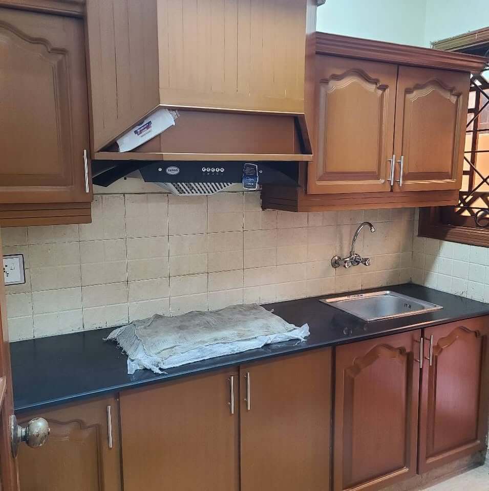 Supreme Luxury Bungalow for Sale in DHA Phase 6, Karachi (6) Elegant kitchen with polished wooden cabinets, black granite countertop, stainless steel sink in DHA Phase 6 bungalow