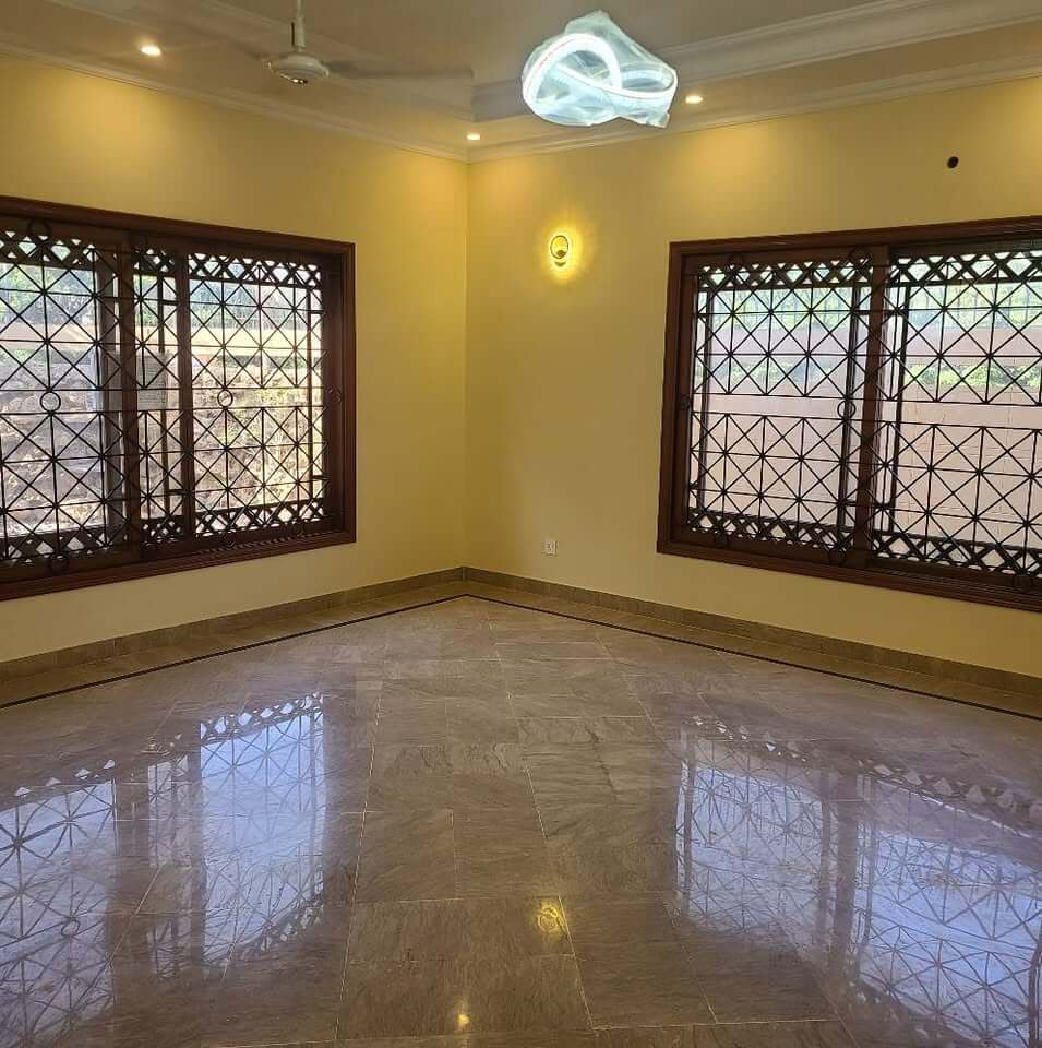 Supreme Luxury Bungalow for Sale in DHA Phase 6, Karachi (9) Corner room in bungalow for sale in DHA Phase 6, Karachi: yellow walls, wooden windows with intricate grills, polished marble