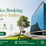 Modern Glass Office Building In Gulistan-E-Jauhar With Surrounding Green Landscaping And Vehicles In The Parking Area.