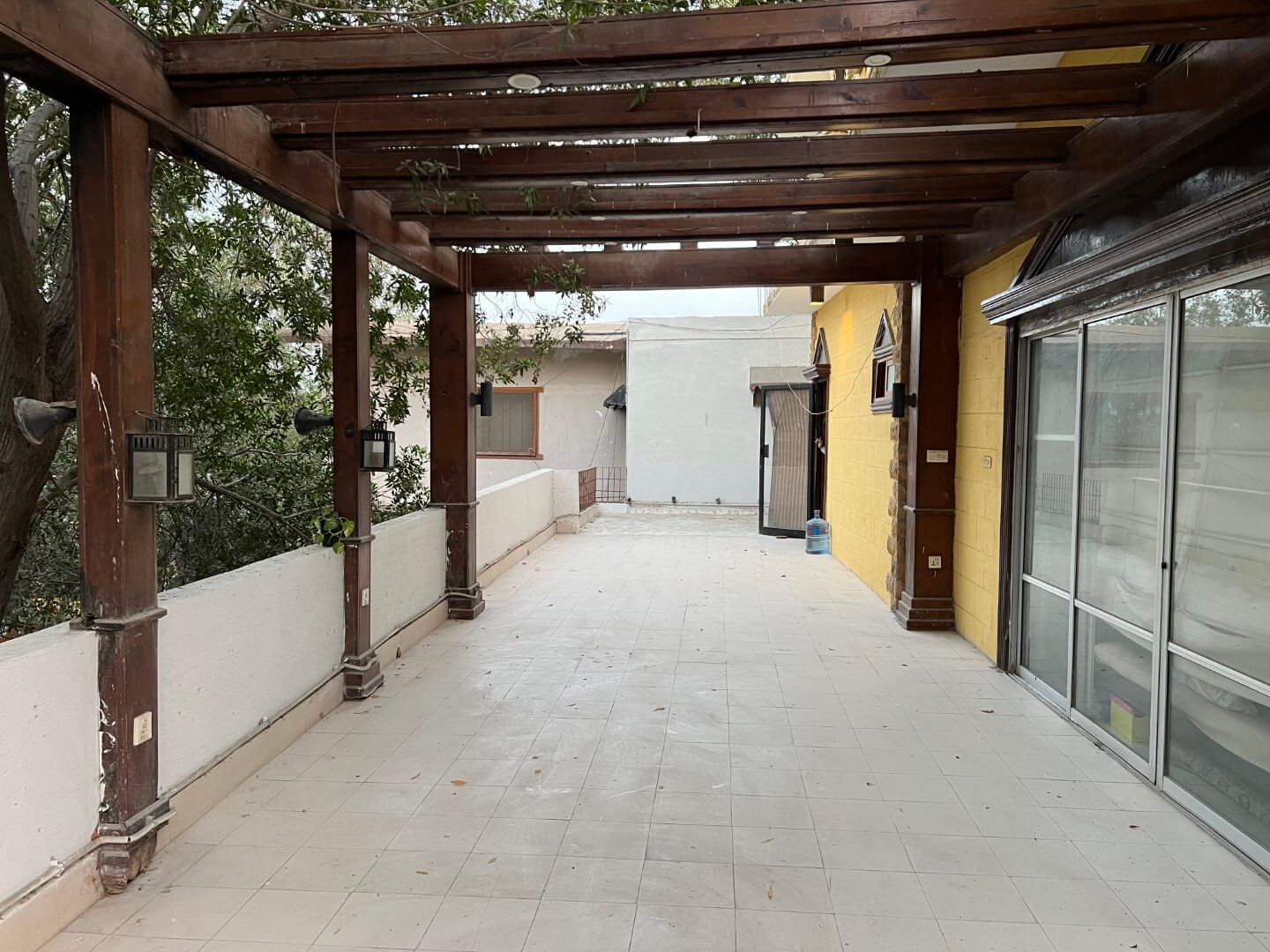 Portion for Rent in DHA Karachi – Fully Furnished Prime Location MaxX Capitals (10) Spacious terrace with wooden pergola, white tiled floor, sliding glass doors in fully furnished portion for rent in DHA Karac