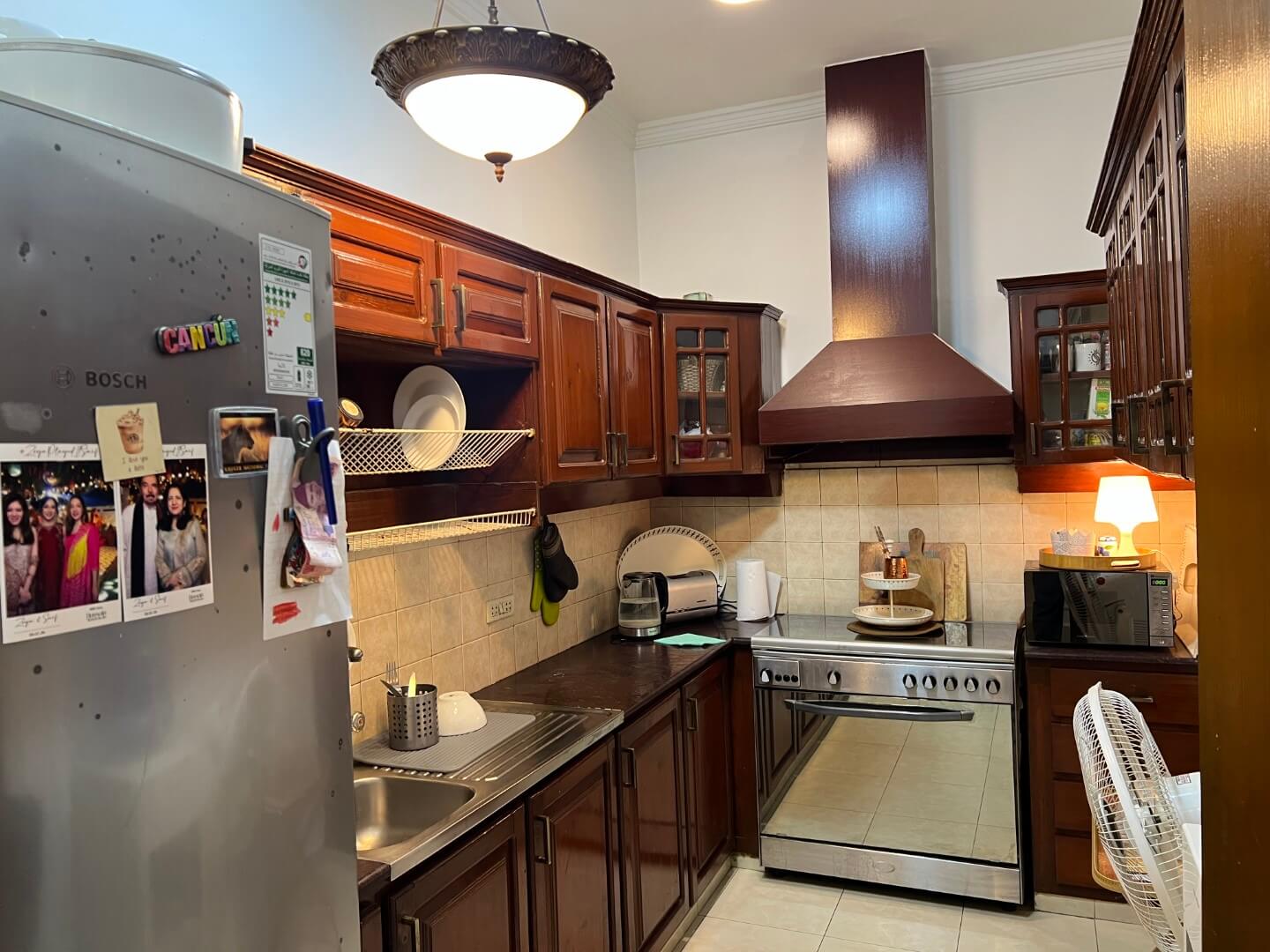 Portion for Rent in DHA Karachi – Fully Furnished Prime Location MaxX Capitals (4) Fully furnished kitchen in DHA Karachi portion for rent with wooden cabinets, Bosch fridge, stainless steel oven, sink and ch