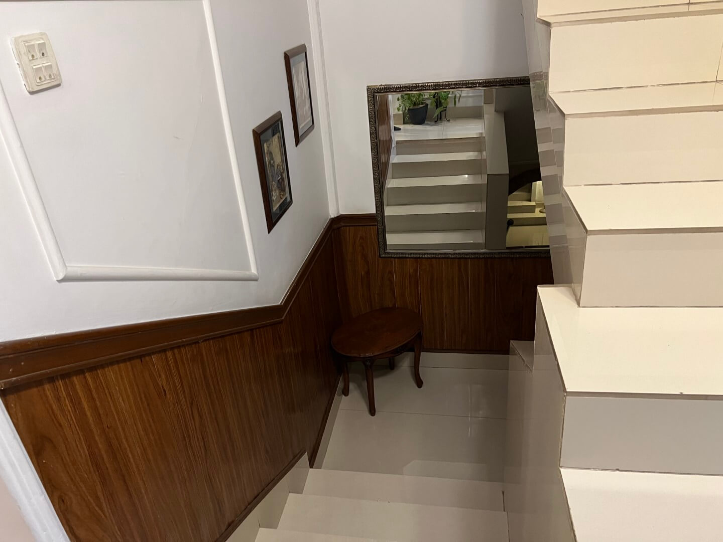 Portion for Rent in DHA Karachi – Fully Furnished Prime Location MaxX Capitals (6) Elegant wooden staircase with paneled walls, handrail, small round table, mirror, and framed art in fully furnished portion f