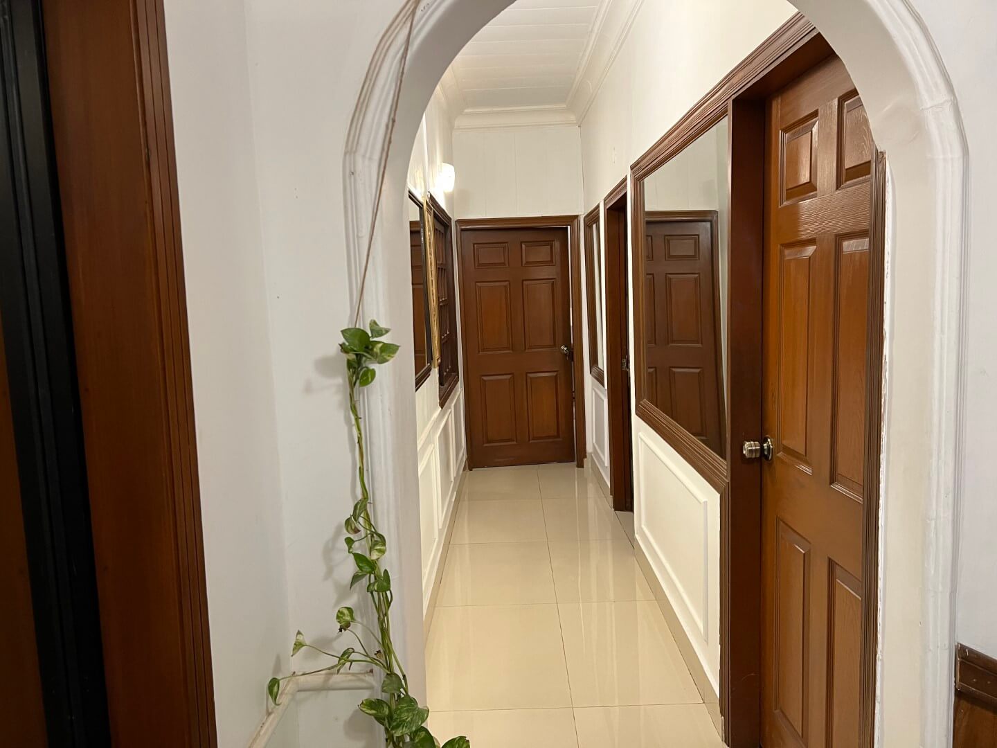 Portion for Rent in DHA Karachi – Fully Furnished Prime Location MaxX Capitals (7) Spacious hallway in fully furnished portion for rent in DHA Karachi featuring arched wooden doors, mirrors, white walls, tile