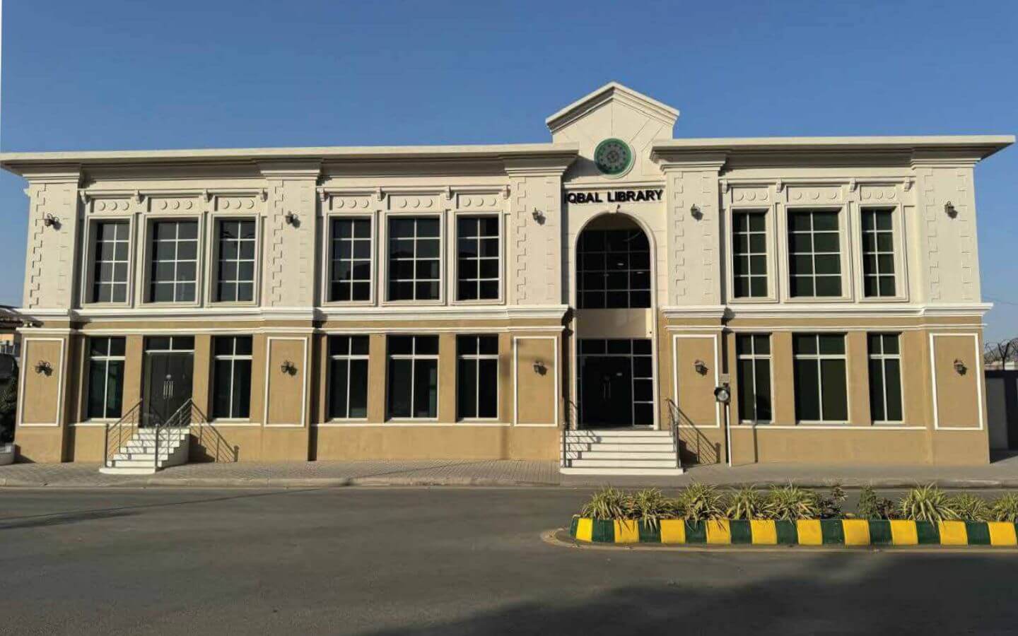 Book Luxury Apartments in Askari 4 Karachi – MaxX Capitals (2) Central Library facade in Askari 4 Karachi, beige building with white trim, large windows, arched entrance, steps and yellow
