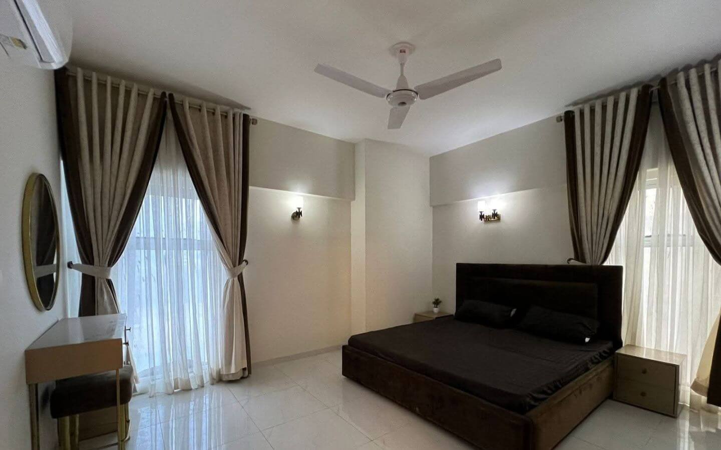 4-Bed Apartment for Sale in Greens 3 Clifton Block 8 MaxX Capitals modern bedroom in Greens 3 Clifton apartment with king bed, curtains, fan, and tiled floor