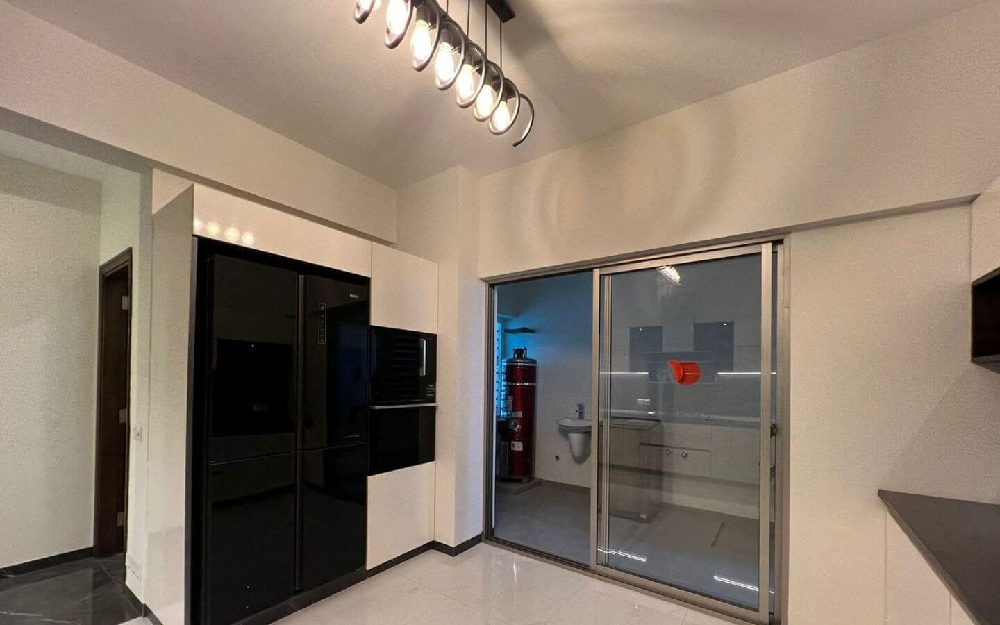 4-Bed Apartment for Sale in Greens 3 Clifton Block 8 MaxX Capitals modern kitchen in Greens 3 Clifton apartment with black built-in appliances and sliding glass door