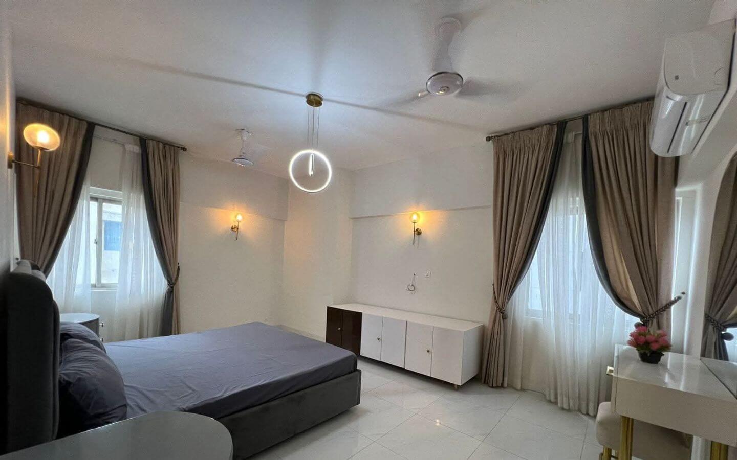 4-Bed Apartment for Sale in Greens 3 Clifton Block 8 MaxX Capitals bedroom in Greens 3 Clifton apartment with twin windows, curtains, ceiling fans and air conditioner
