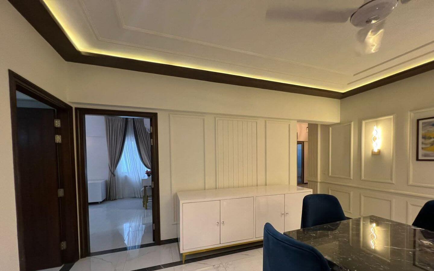 4-Bed Apartment for Sale in Greens 3 Clifton Block 8 MaxX Capitals dining room with marble table, upholstered chairs, paneled walls, and cove lighting in Greens 3 Clifton apartme