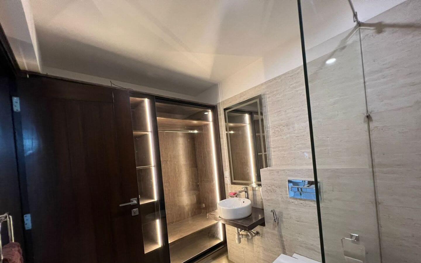 4-Bed Apartment for Sale in Greens 3 Clifton Block 8 MaxX Capitals bathroom in 4 bed apartment for sale Greens 3 Clifton, with glass shower, vanity, and lit wardrobe area
